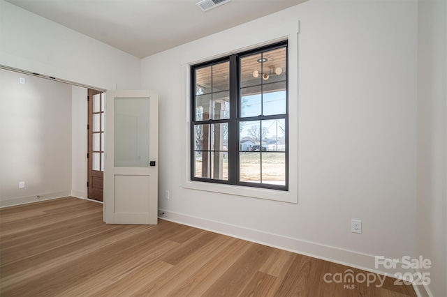 empty room featuring light wood-style flooring, visible vents, and baseboards