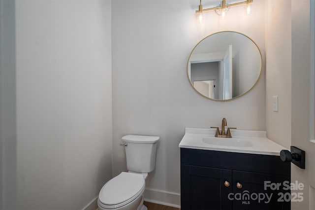 half bathroom featuring baseboards, vanity, and toilet