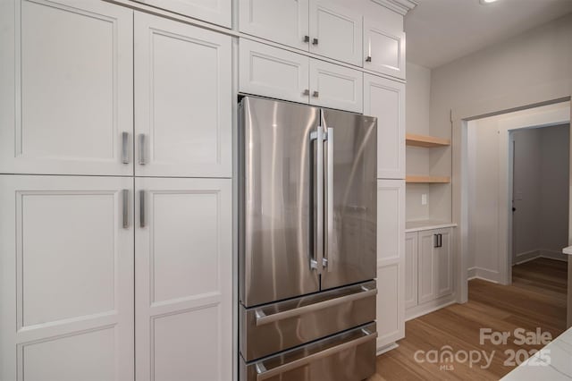 kitchen with open shelves, light countertops, freestanding refrigerator, white cabinets, and light wood-type flooring