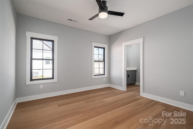 unfurnished bedroom with baseboards, visible vents, light wood finished floors, and ensuite bathroom