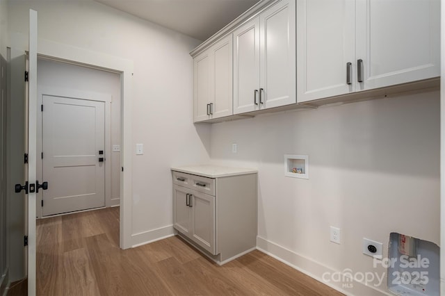 washroom featuring hookup for a washing machine, light wood-style flooring, baseboards, cabinet space, and electric dryer hookup