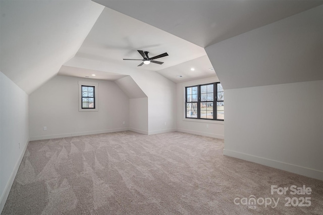 additional living space with a ceiling fan, light carpet, vaulted ceiling, and baseboards