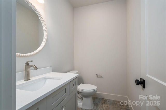 bathroom featuring toilet, baseboards, and vanity