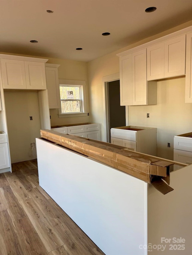 kitchen with light hardwood / wood-style floors and white cabinets