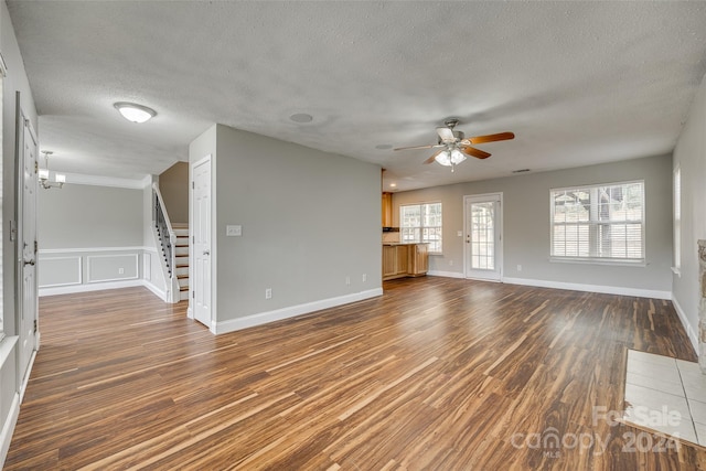 unfurnished living room with dark wood-type flooring, a textured ceiling, and ceiling fan with notable chandelier