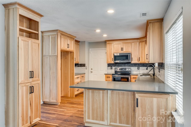 kitchen with hardwood / wood-style flooring, sink, backsplash, light brown cabinets, and appliances with stainless steel finishes