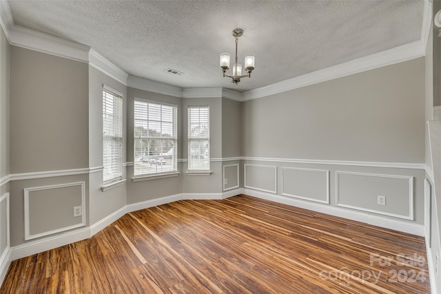 unfurnished room featuring hardwood / wood-style floors, a notable chandelier, a textured ceiling, and crown molding