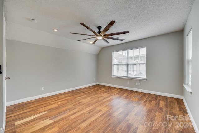 unfurnished room featuring light hardwood / wood-style floors, ceiling fan, a textured ceiling, and lofted ceiling