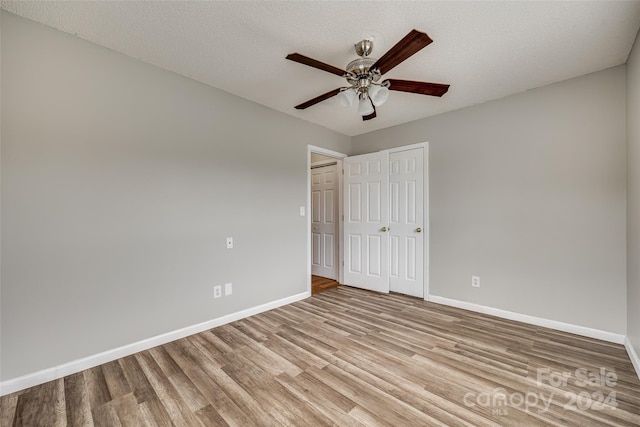 unfurnished bedroom with ceiling fan, a textured ceiling, and light wood-type flooring