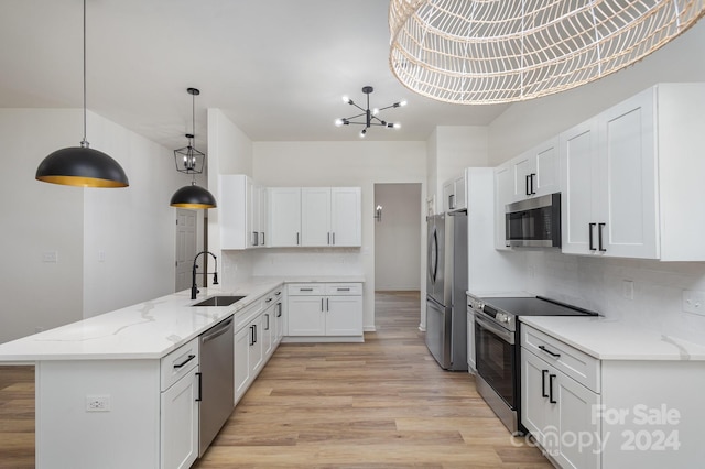 kitchen with appliances with stainless steel finishes, sink, hanging light fixtures, white cabinets, and light hardwood / wood-style flooring