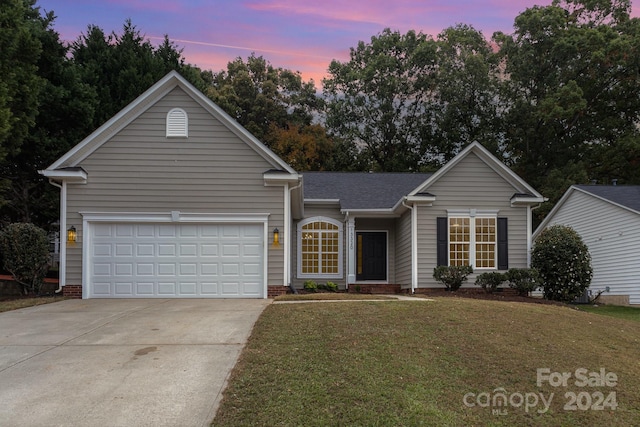 ranch-style home featuring a lawn and a garage