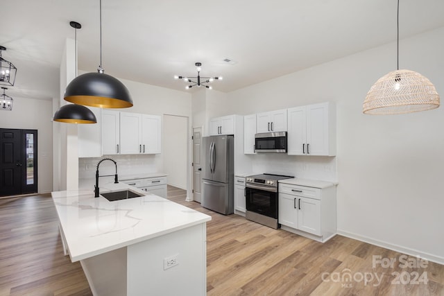 kitchen featuring white cabinets, hanging light fixtures, stainless steel appliances, and sink