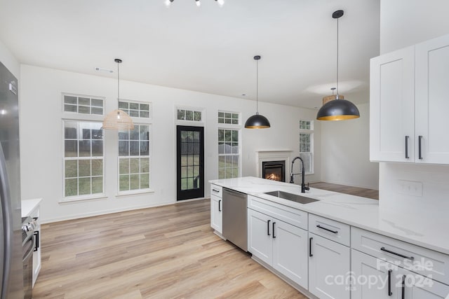 kitchen featuring pendant lighting, sink, stainless steel dishwasher, and white cabinets