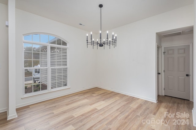 unfurnished dining area with a chandelier and light hardwood / wood-style flooring