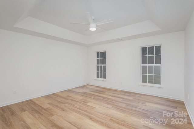 unfurnished room with light hardwood / wood-style flooring, a tray ceiling, and ceiling fan