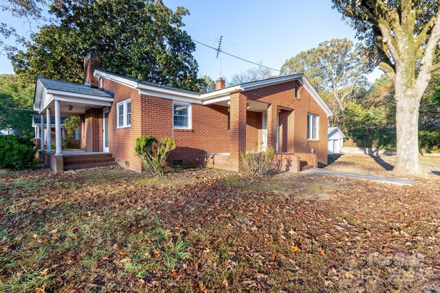 24947 Nc-24/27 Hwy, Albemarle, NC 28001 - view of front facade with a porch, crawl space, a chimney, brick siding, and an outdoor structure