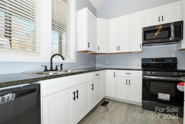 kitchen with lofted ceiling, black appliances, sink, light wood-type flooring, and white cabinetry