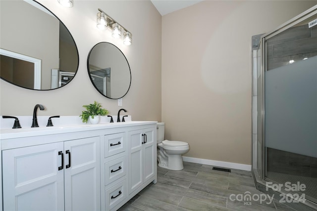 bathroom featuring a shower with door, vanity, wood-type flooring, and toilet