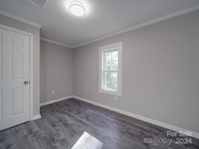 spare room with dark hardwood / wood-style flooring and crown molding