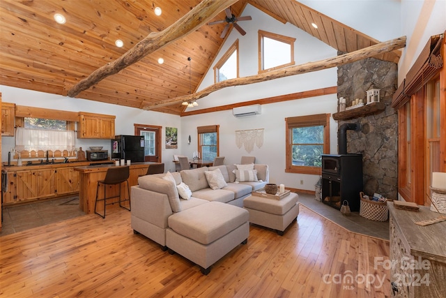 living room with light hardwood / wood-style floors, a wood stove, a healthy amount of sunlight, and high vaulted ceiling