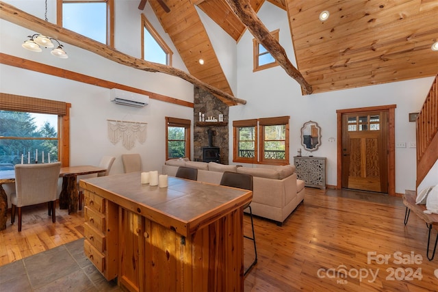 kitchen featuring a healthy amount of sunlight, an AC wall unit, high vaulted ceiling, and a wood stove