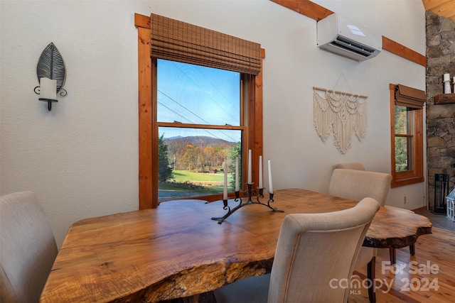 dining area featuring hardwood / wood-style flooring, an AC wall unit, and a fireplace