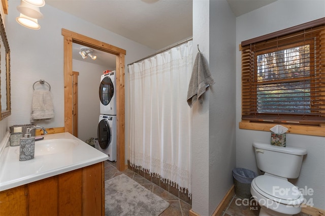 bathroom with vanity, stacked washer and dryer, toilet, and tile patterned floors