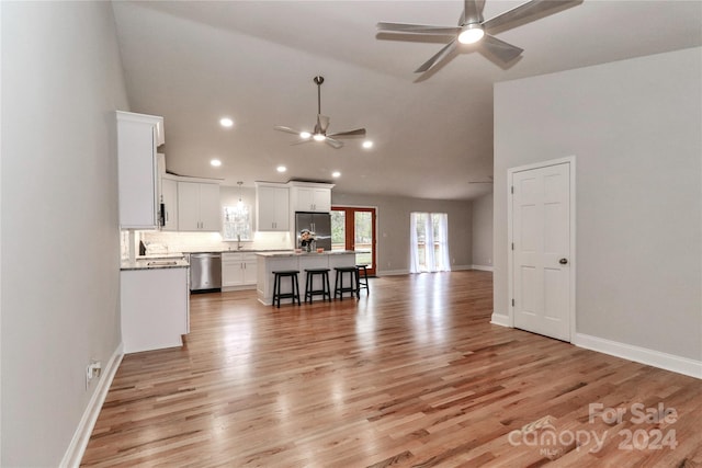 kitchen with stainless steel appliances, white cabinetry, a kitchen island with sink, and light hardwood / wood-style flooring