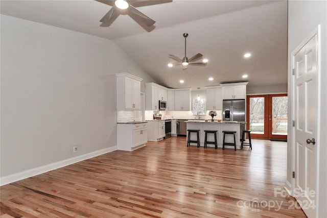 kitchen with a center island, stainless steel appliances, white cabinetry, and light hardwood / wood-style floors