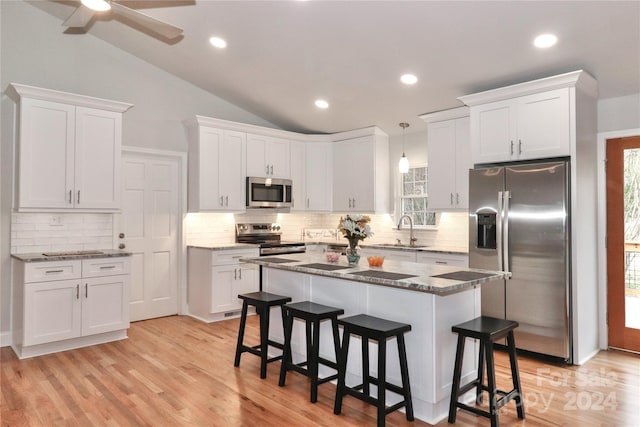 kitchen featuring stainless steel appliances, vaulted ceiling, and white cabinetry