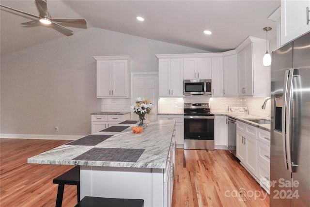 kitchen featuring pendant lighting, light hardwood / wood-style floors, appliances with stainless steel finishes, and vaulted ceiling