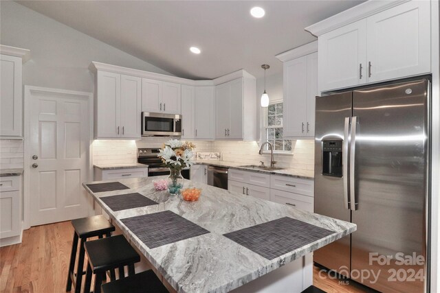 kitchen featuring a breakfast bar, sink, hanging light fixtures, white cabinetry, and stainless steel appliances