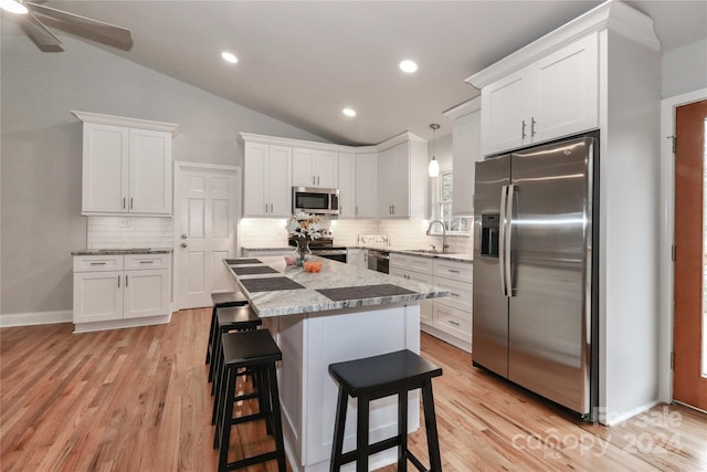 kitchen with white cabinets, appliances with stainless steel finishes, light hardwood / wood-style floors, and lofted ceiling