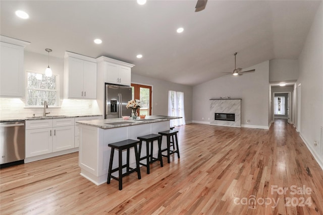 kitchen with appliances with stainless steel finishes, vaulted ceiling, sink, pendant lighting, and light hardwood / wood-style floors