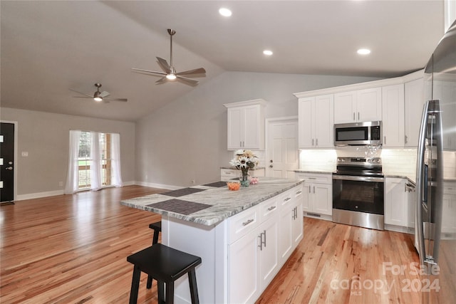 kitchen featuring white cabinets, stainless steel appliances, light hardwood / wood-style flooring, and lofted ceiling