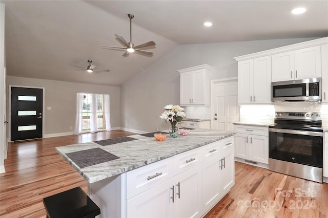 kitchen with white cabinets, stainless steel appliances, vaulted ceiling, and light hardwood / wood-style flooring