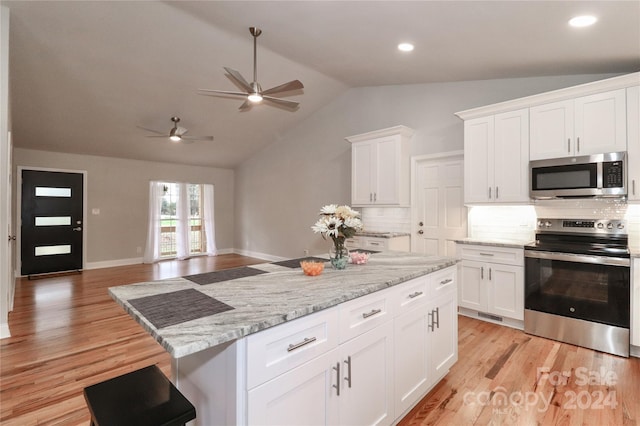 kitchen featuring appliances with stainless steel finishes, white cabinetry, vaulted ceiling, and light hardwood / wood-style floors