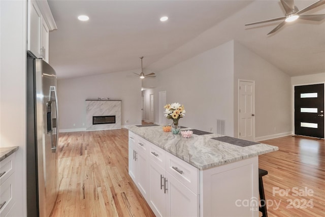 kitchen with stainless steel refrigerator with ice dispenser, vaulted ceiling, light hardwood / wood-style flooring, and white cabinetry