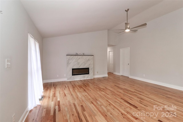 unfurnished living room featuring a high end fireplace, light hardwood / wood-style floors, high vaulted ceiling, and ceiling fan