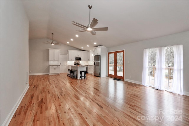 unfurnished living room with ceiling fan, light hardwood / wood-style floors, and vaulted ceiling