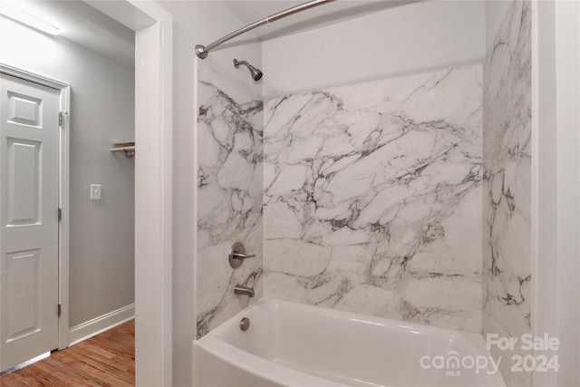 bathroom featuring wood-type flooring and tiled shower / bath