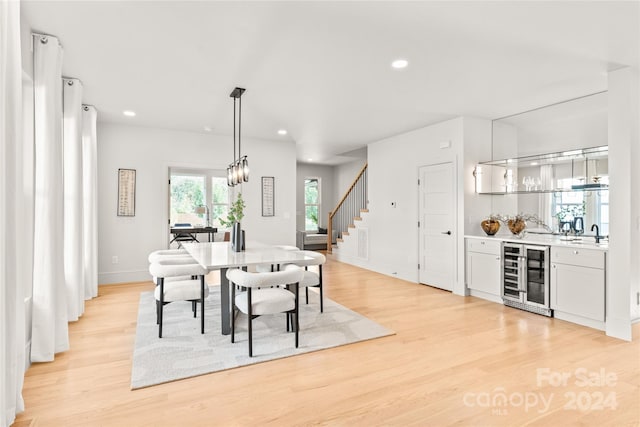 dining area with beverage cooler, indoor wet bar, and light wood-type flooring