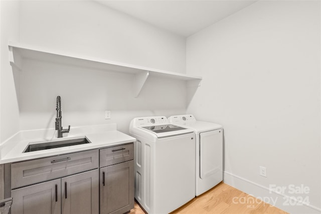 washroom with washer and clothes dryer, light wood-type flooring, cabinets, and sink