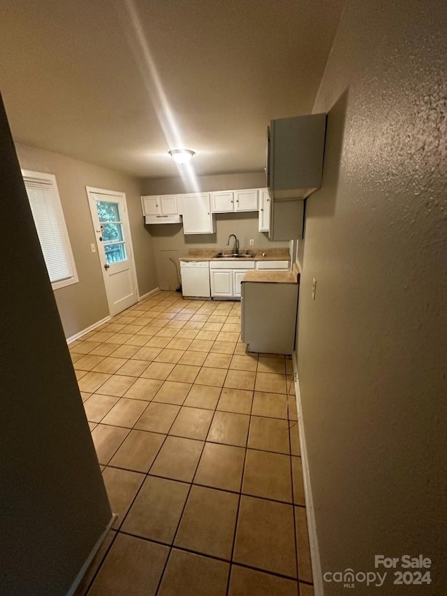 kitchen with white cabinetry, light tile patterned floors, sink, and dishwasher