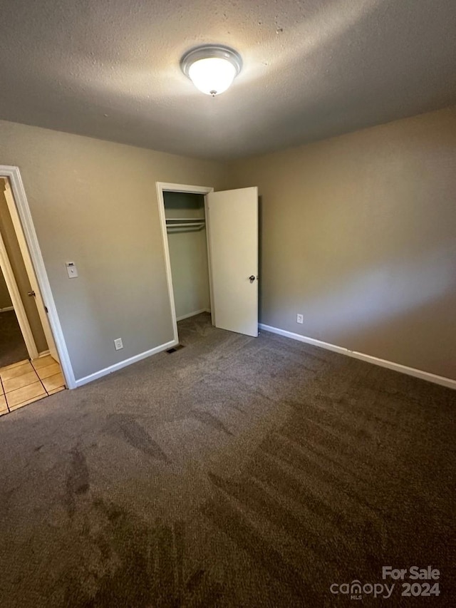 unfurnished bedroom with a closet, a textured ceiling, and light colored carpet