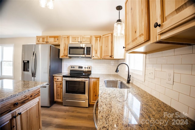 kitchen featuring sink, stainless steel appliances, backsplash, light hardwood / wood-style floors, and decorative light fixtures