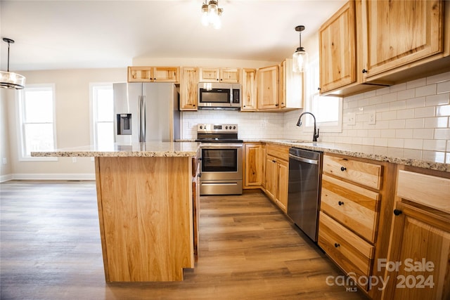 kitchen featuring dark wood-type flooring, a center island, hanging light fixtures, and appliances with stainless steel finishes