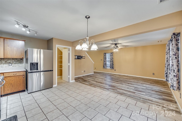 kitchen with stainless steel appliances, tasteful backsplash, pendant lighting, ceiling fan with notable chandelier, and light wood-type flooring