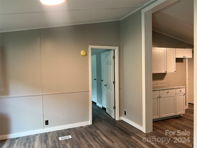 hallway with ornamental molding, vaulted ceiling, and dark wood-type flooring