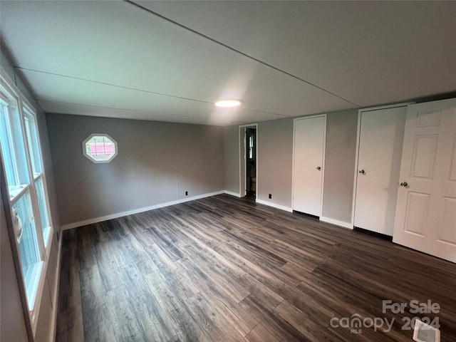 unfurnished bedroom featuring dark wood-type flooring and multiple closets